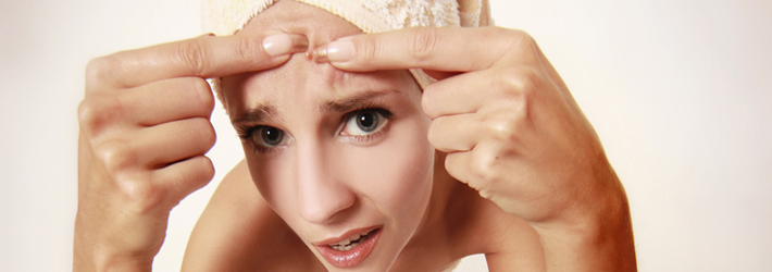 Frau dr&uuml;ckt Pickel an ihrer Stirn aus